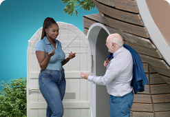 A female talking to an elderly male outside an open door of a building.